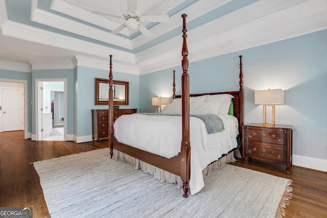 bedroom with ornamental molding, baseboards, a tray ceiling, and wood finished floors