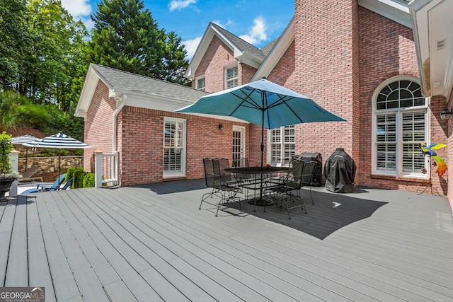 wooden terrace featuring area for grilling and outdoor dining space