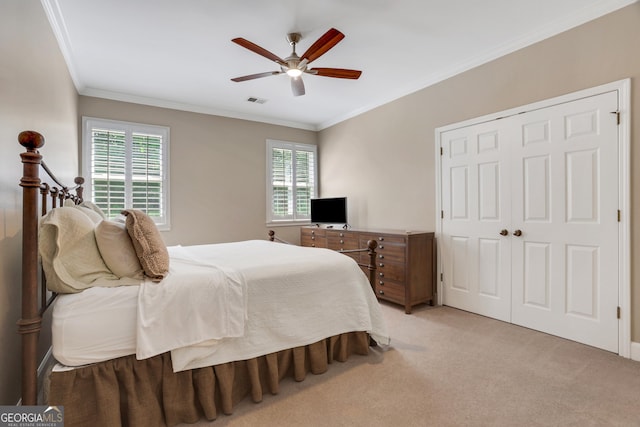 bedroom featuring visible vents, ornamental molding, light carpet, a closet, and a ceiling fan