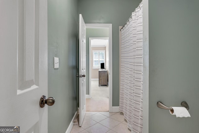 corridor with light tile patterned floors and baseboards