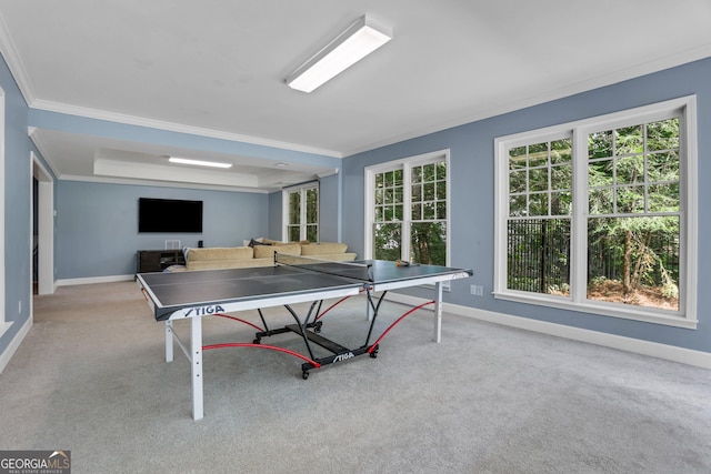 rec room featuring a tray ceiling, baseboards, carpet floors, and crown molding