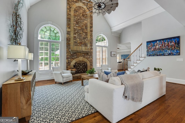 living area with high vaulted ceiling, wood finished floors, and stairs