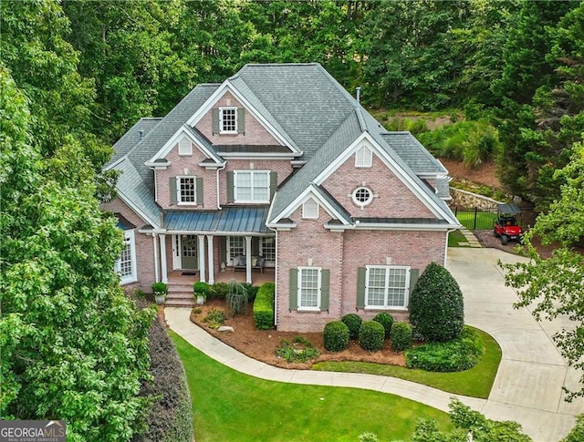 view of front of house featuring brick siding, covered porch, a front yard, and roof with shingles