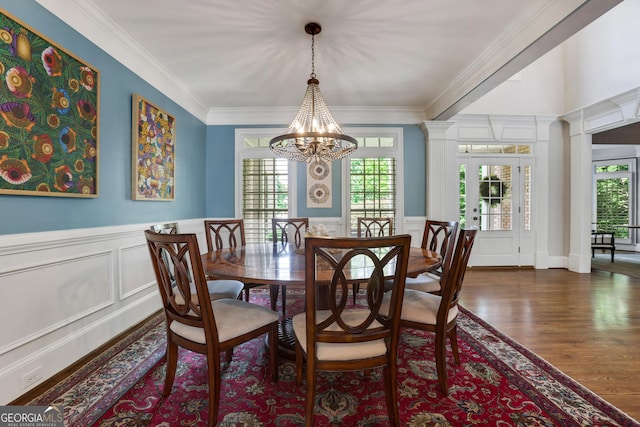 dining area with an inviting chandelier, dark wood-type flooring, crown molding, and a healthy amount of sunlight