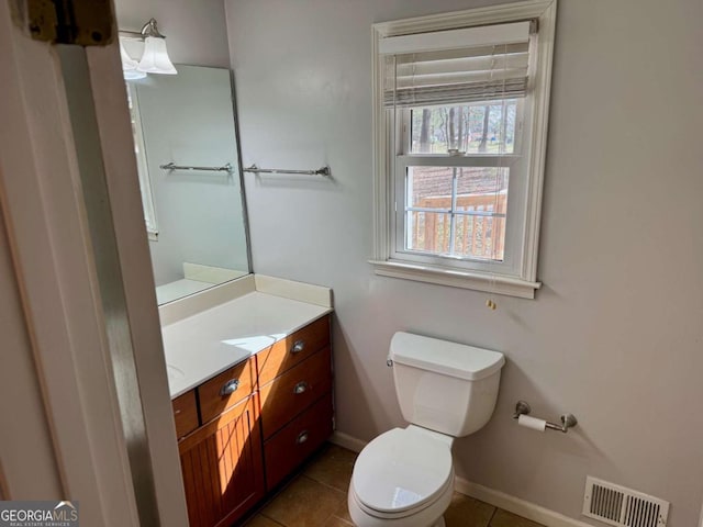 half bathroom with visible vents, toilet, tile patterned flooring, baseboards, and vanity