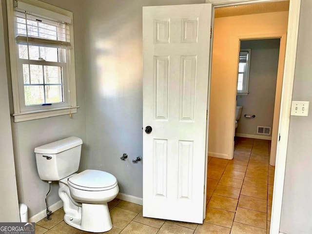 bathroom with tile patterned floors, visible vents, toilet, and baseboards