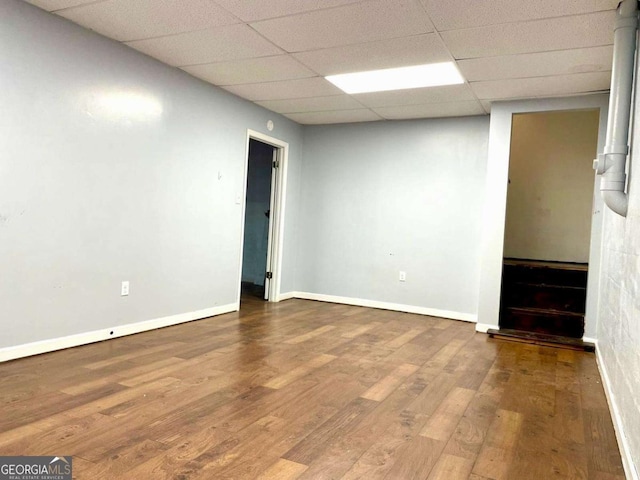 spare room featuring a paneled ceiling, baseboards, and wood finished floors