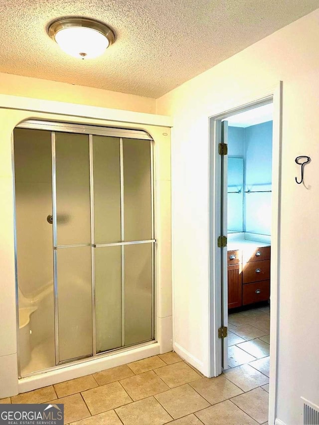 bathroom with visible vents, a textured ceiling, a stall shower, and tile patterned flooring