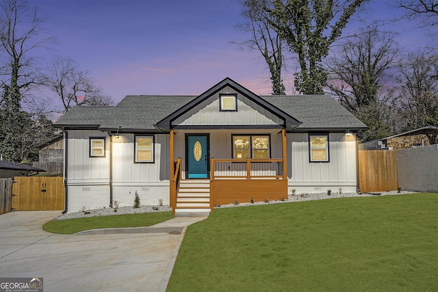 modern farmhouse style home with a yard, a gate, covered porch, and a shingled roof