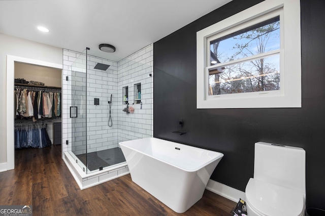 bathroom with a freestanding tub, wood finished floors, a shower stall, and a walk in closet