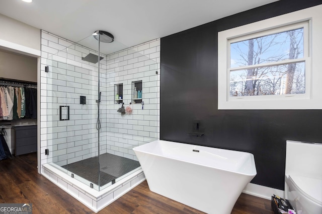 full bath with a stall shower, a soaking tub, and wood finished floors