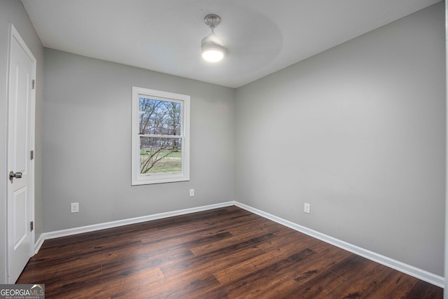 empty room featuring baseboards and dark wood finished floors