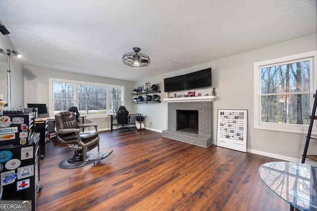 living area featuring a fireplace, a textured ceiling, wood finished floors, and baseboards