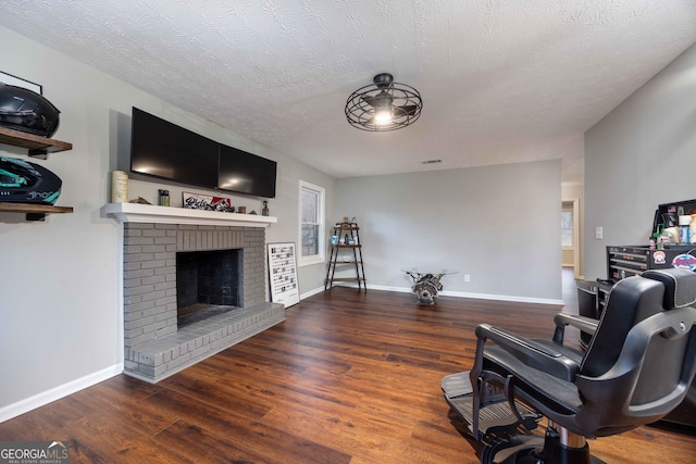 living room with a textured ceiling, baseboards, wood finished floors, and a fireplace