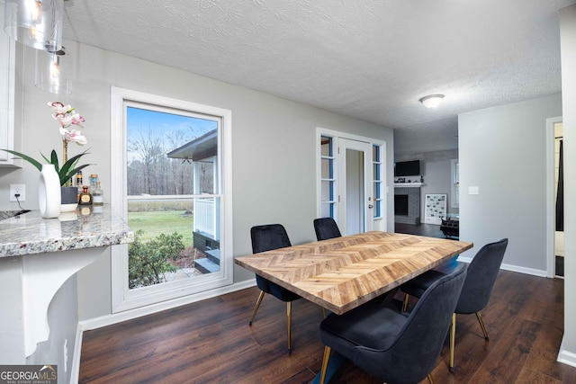 dining room featuring dark wood-style floors, a textured ceiling, and baseboards
