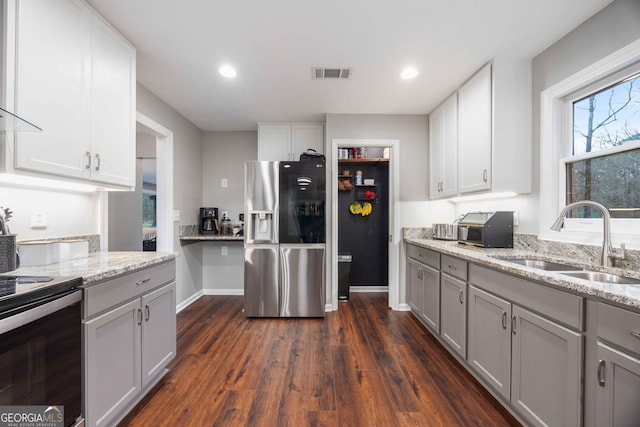kitchen with light stone countertops, electric range, a sink, visible vents, and stainless steel refrigerator with ice dispenser