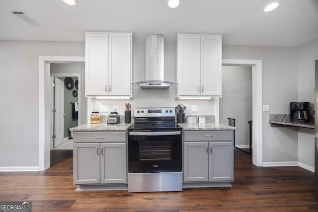kitchen featuring baseboards, visible vents, stainless steel electric stove, and wall chimney range hood