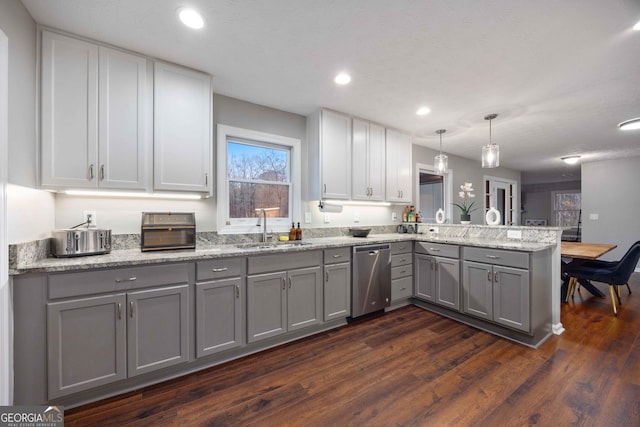 kitchen featuring dishwasher, a sink, gray cabinetry, a peninsula, and dark wood-style floors