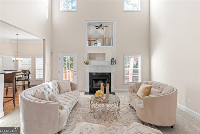 living room featuring a high ceiling, plenty of natural light, baseboards, and a high end fireplace