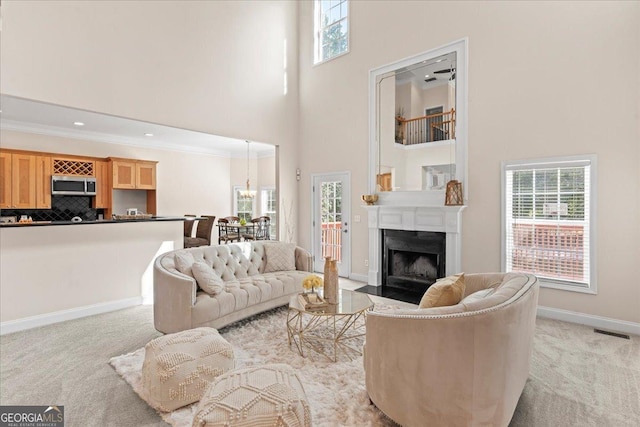 living area featuring visible vents, a fireplace with flush hearth, light colored carpet, and a towering ceiling