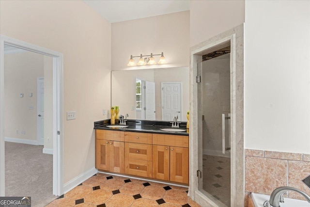 bathroom featuring double vanity, a stall shower, baseboards, and a sink