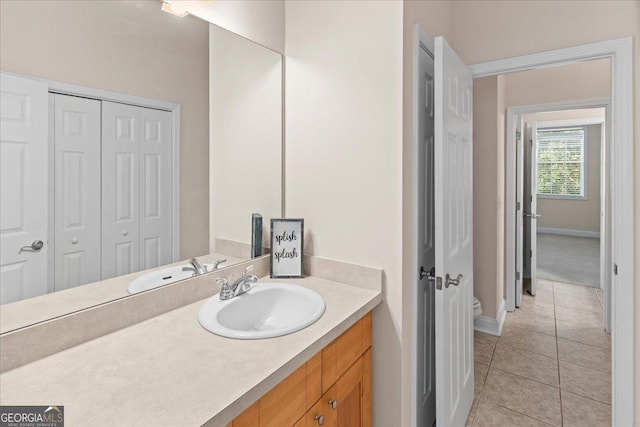 bathroom with tile patterned flooring, toilet, vanity, and baseboards