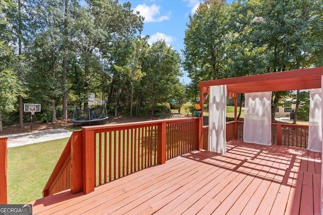 wooden deck featuring a trampoline and a yard