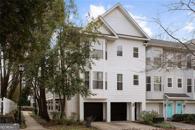 multi unit property featuring a garage and concrete driveway