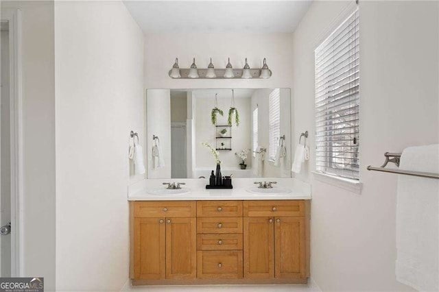 full bath featuring a sink, a shower with shower door, and double vanity