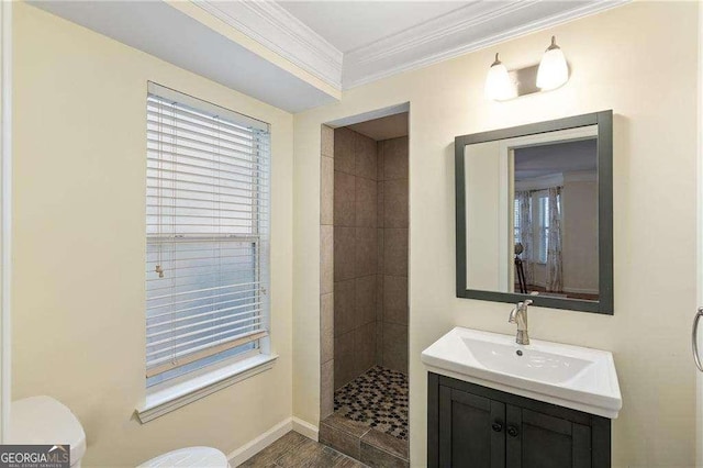 full bath featuring vanity, baseboards, a tile shower, crown molding, and toilet