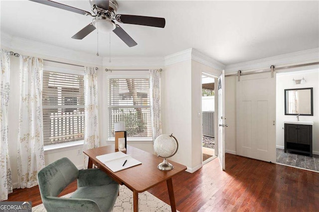 office featuring a barn door, crown molding, wood finished floors, and a sink