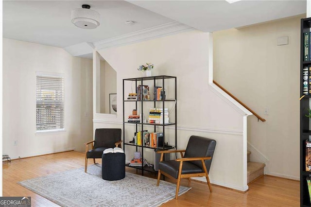 living area featuring stairway, crown molding, baseboards, and wood finished floors