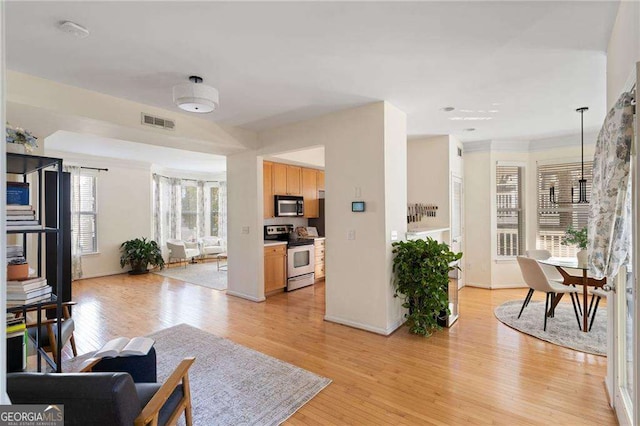 living area with light wood-type flooring, visible vents, and baseboards