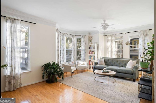 living area featuring ceiling fan, baseboards, ornamental molding, and hardwood / wood-style flooring