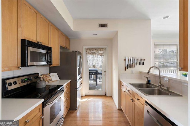 kitchen featuring visible vents, a sink, stainless steel appliances, light countertops, and backsplash