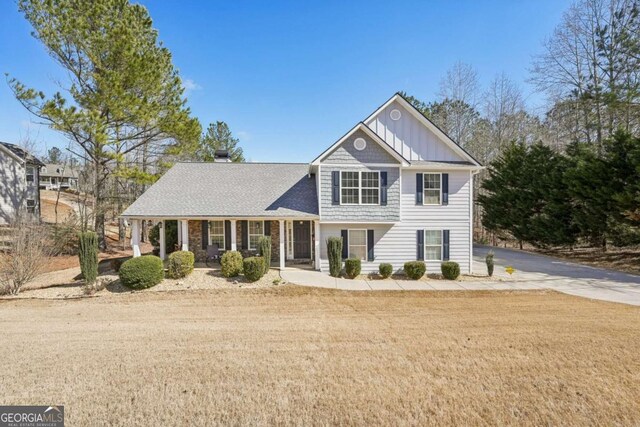 view of front of house featuring board and batten siding, driveway, and a front yard