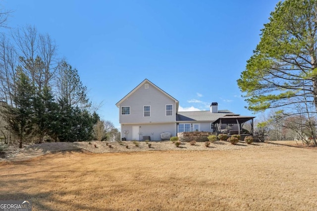 back of house featuring a yard, a garage, and a chimney