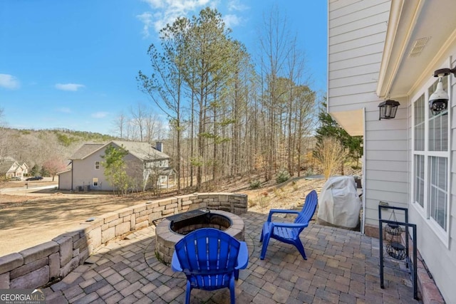 view of patio with area for grilling and a fire pit