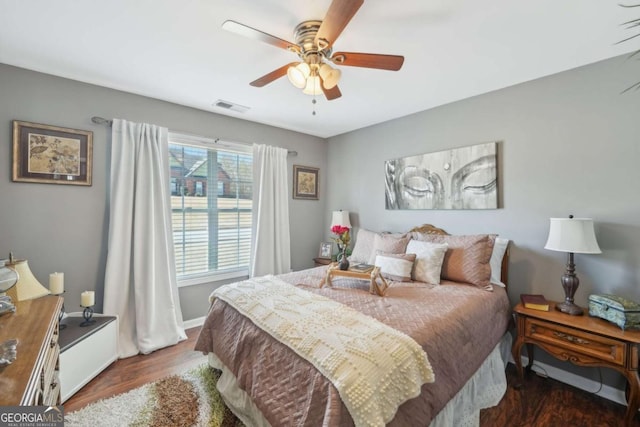 bedroom featuring baseboards, wood finished floors, visible vents, and ceiling fan