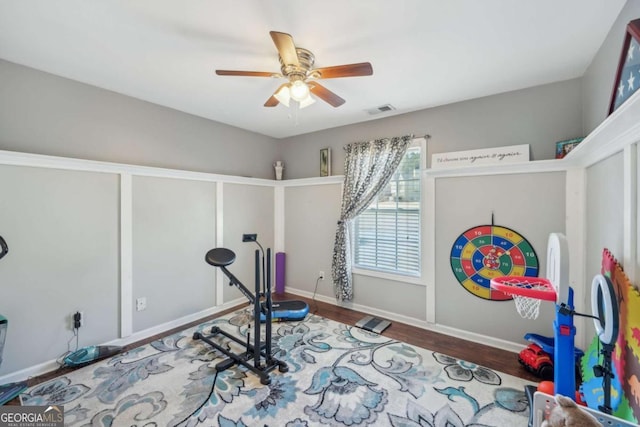 exercise room featuring visible vents, baseboards, wood finished floors, and a ceiling fan