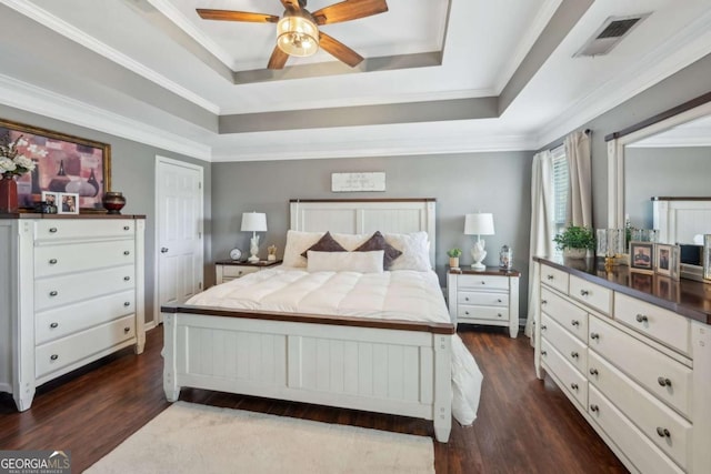 bedroom with visible vents, crown molding, a tray ceiling, and dark wood-style flooring