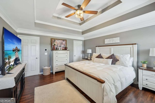 bedroom featuring dark wood-style floors, a tray ceiling, ceiling fan, a closet, and crown molding