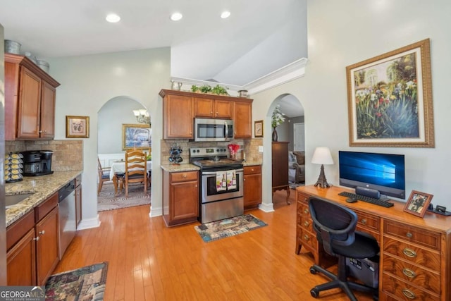 kitchen featuring arched walkways, backsplash, appliances with stainless steel finishes, and light wood-type flooring