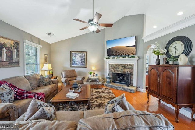 living area featuring visible vents, vaulted ceiling, a fireplace, wood finished floors, and a ceiling fan