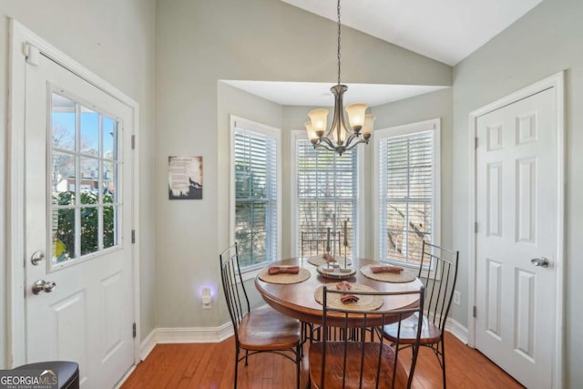 dining area featuring light wood-type flooring, baseboards, an inviting chandelier, and vaulted ceiling