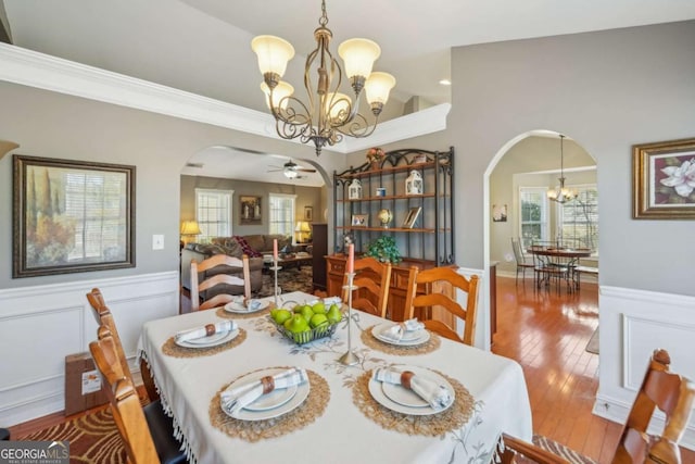 dining area with arched walkways, wainscoting, and hardwood / wood-style floors