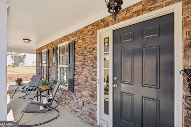 entrance to property featuring a porch and stone siding