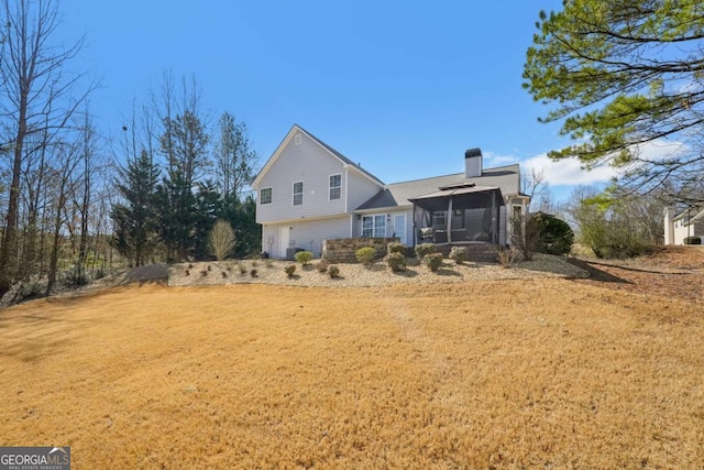 exterior space featuring a garage, a lawn, a chimney, and a sunroom