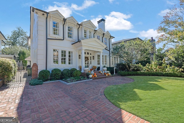 view of front of home featuring a front yard, a gate, a chimney, and stucco siding