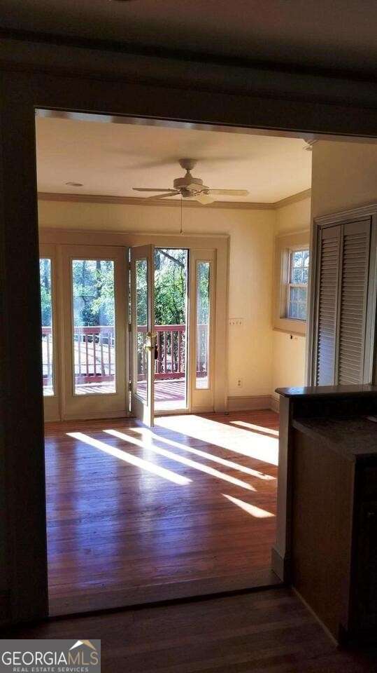 entryway with crown molding, wood finished floors, baseboards, and ceiling fan